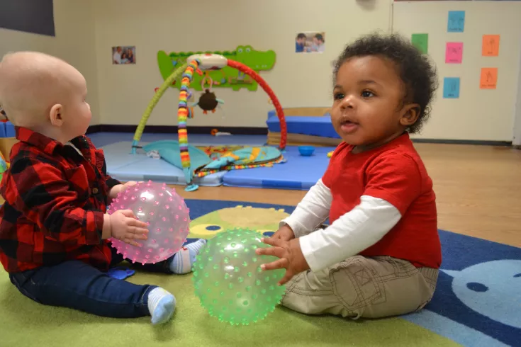Two babies holding a ball
